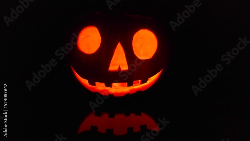 Close-up on a Jack O' Lantern glowing in the dark. photo