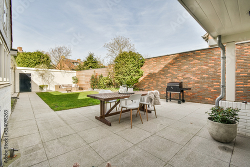 Neat paved patio with sitting area and small garden near wooden fence photo