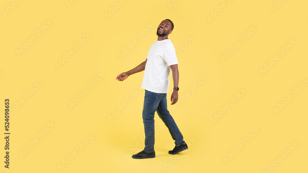 Happy Black Male Walking Posing In Studio Over Yellow Background Happy Black Male Walking Posing In Studio Over Yellow Background