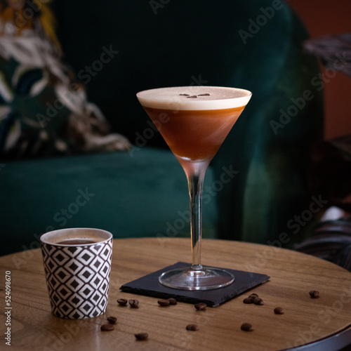 espresso martini cocktail with foam and three coffee beans over wood table with coffee cup