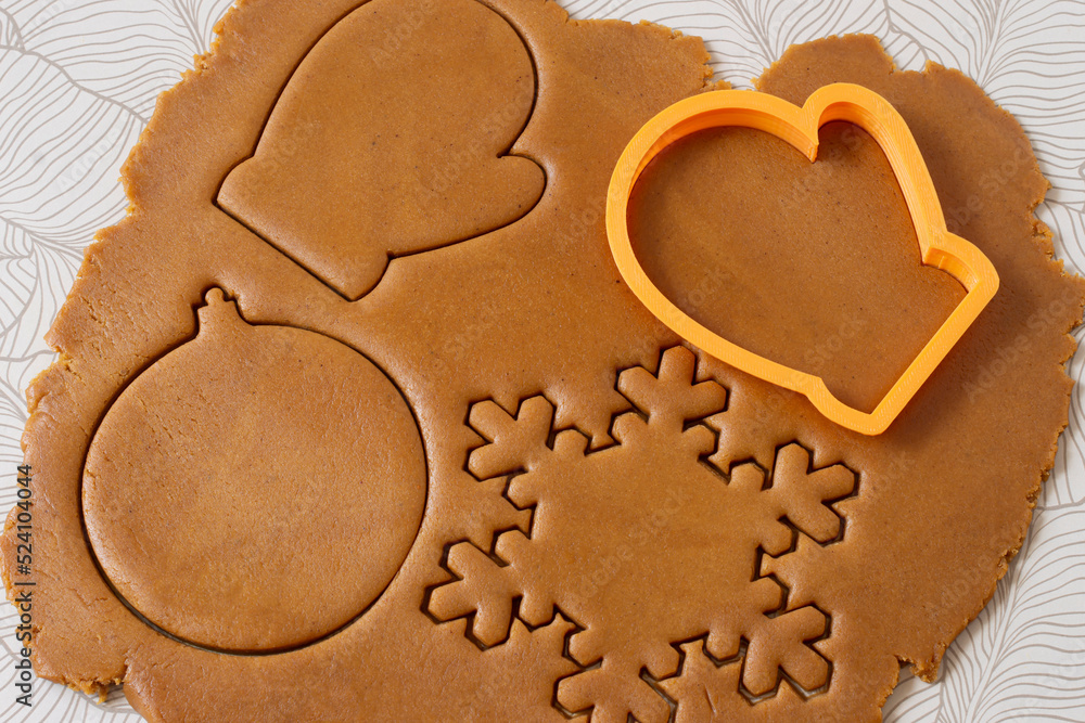 Cutting out Christmas gingerbread from dark honey dough Cutting out Christmas gingerbread from dark honey dough