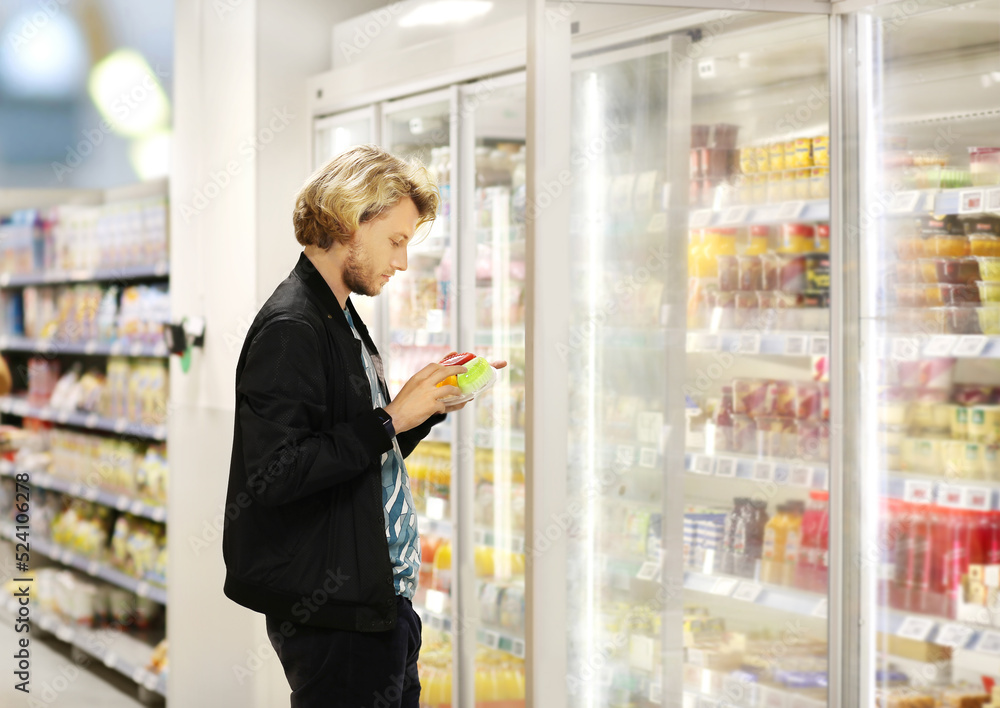  Man choosing frozen food from a supermarket freezer	, reading product information