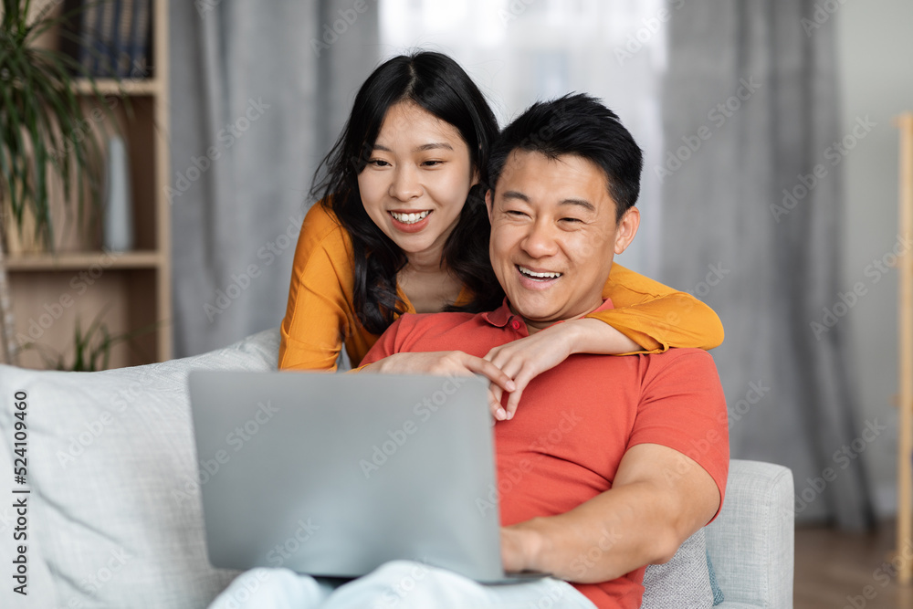Positive asian couple using computer at home, copy space Positive asian couple using computer at home, copy space