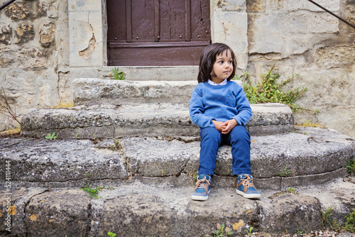 Little handsome baby boy sitting on ancient stone stairs outdoor in old city © svittlana