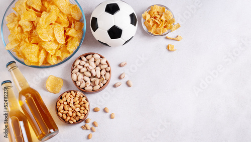 Beer and snack on gray table with football ball, football game night food, copy space photo