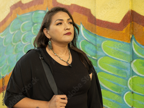 Native teacher poses in front of school mural