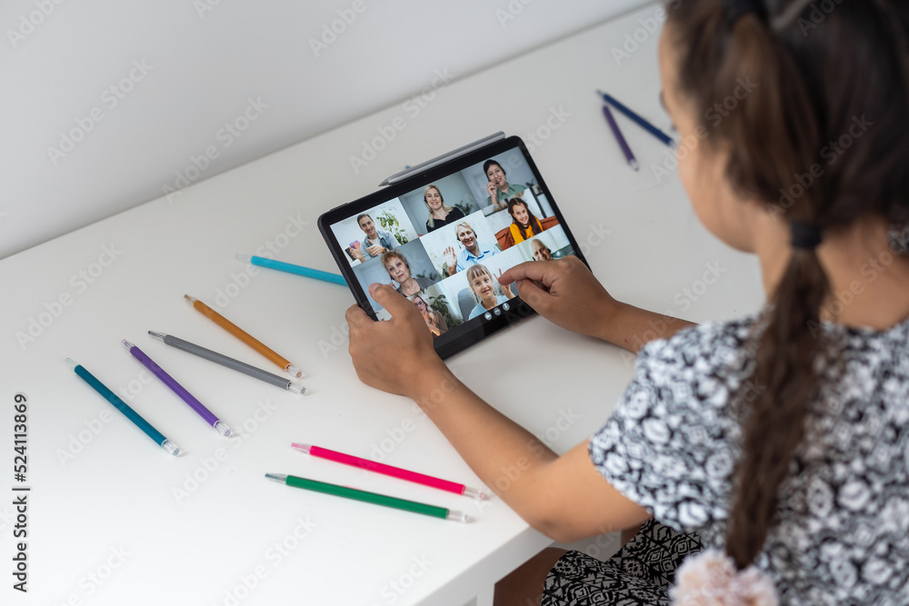 Back to school. Happy little schoolgirl sitting at her Desk. The girl does her homework using a tablet computer. online education