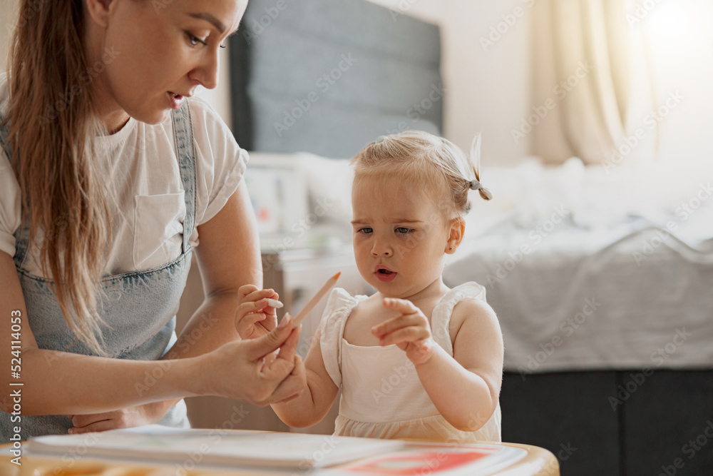 Little smiling girl painting with her mother at home while spending time together Little smiling girl painting with her mother at home while spending time together