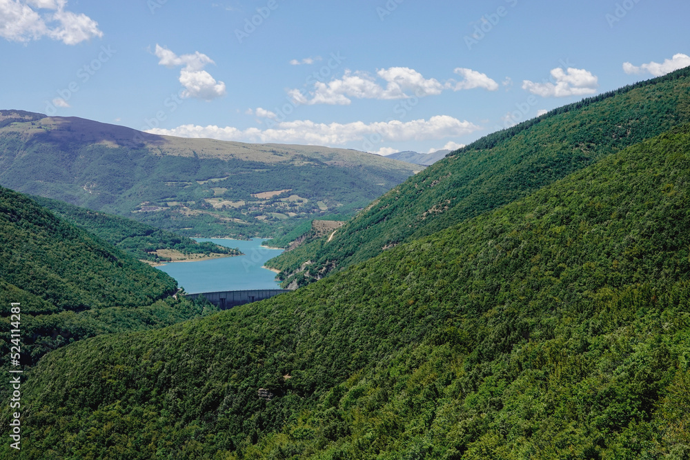Panorama of the Fiastra Lake on the Sibillini Mountains in Marche. The lake is in the middle of a green forest. Italy
