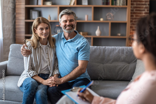 Smiling mature caucasian man and lady hugs at meeting with psychologist in office clinic interior