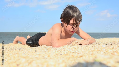 Teenage boy lies on the beach by the sea and sunbathes