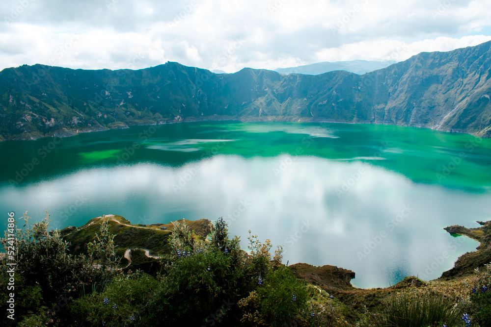 A cloudy day at Quilotoa crater lagoon in Latacunga, Ecuador. Touristic destination with turquoise water reflecting the sky. Ecology and hiking concept.