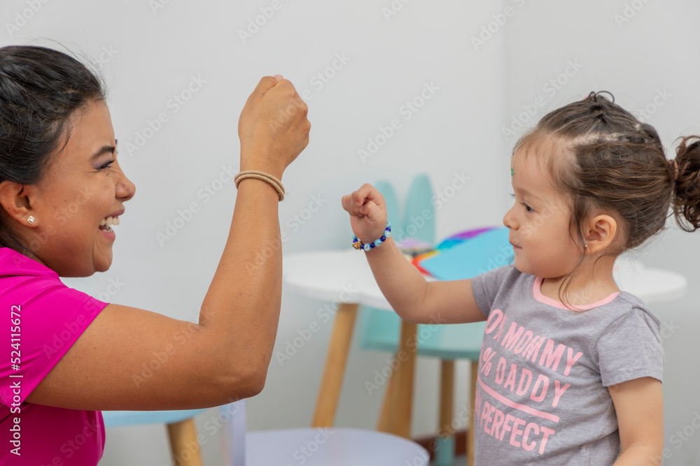a girl and a woman bumping their fists after finishing their activities in preschool a girl and a woman bumping their fists after finishing their activities in preschool