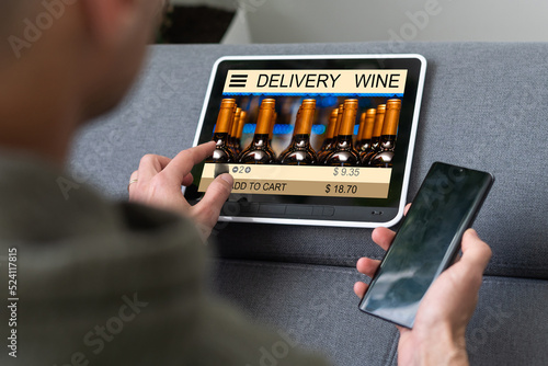 Person holding tablet and buying wine online.