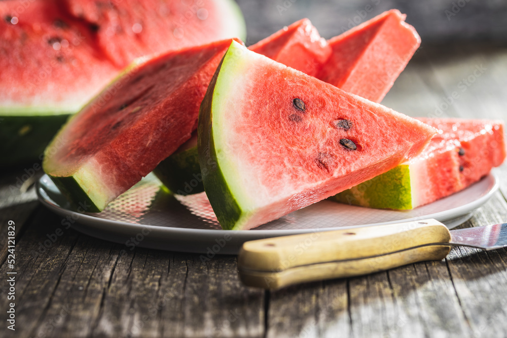 Slices of red watermelon on plate on wooden table. Slices of red watermelon on plate on wooden table.