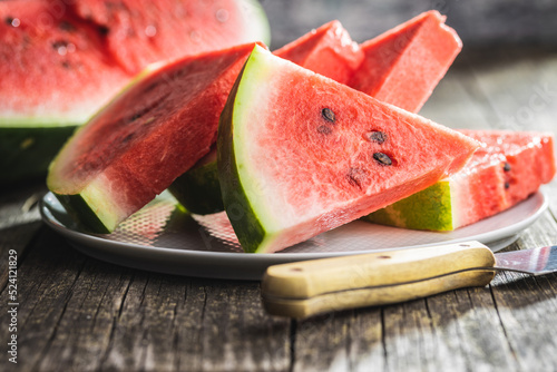 Slices of red watermelon on plate on wooden table.