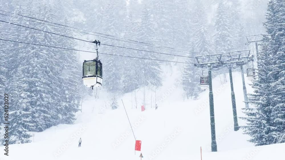 Cabins of the ski lift move on a rope way during snowfall Cabins of the ski lift move on a rope way during snowfall