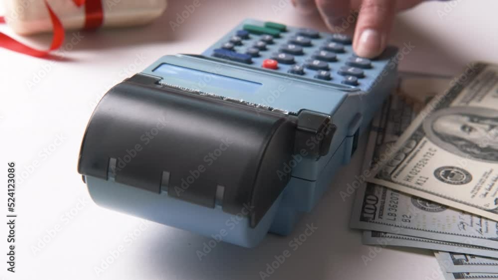 The seller enters the amount into the cash register in the retail store, prints the receipt and cuts the receipt to the buyer. A woman's hand presses the pos terminal button The seller enters the amount into the cash register in the retail store, prints the receipt and cuts the receipt to the buyer. A woman's hand presses the pos terminal button