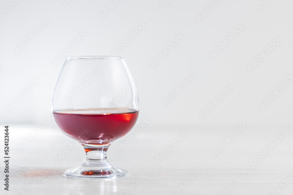 A glass of cognac or brandy on a light background. Empty space for the copy space on the right A glass of cognac or brandy on a light background. Empty space for the copy space on the right