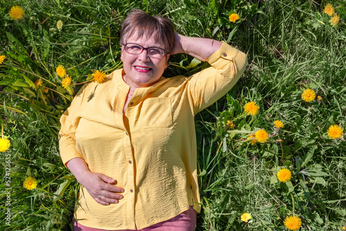 Grandmother lies in the grass and enjoys the spring nature.