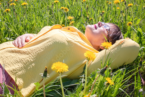 Grandmother lies in the grass and enjoys the spring nature.
