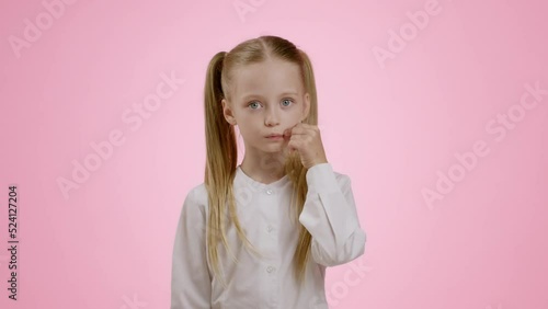 Kids and privacy. Studio portrait of mysterious little girl with ponytails zipping her lips and showing hush gesture