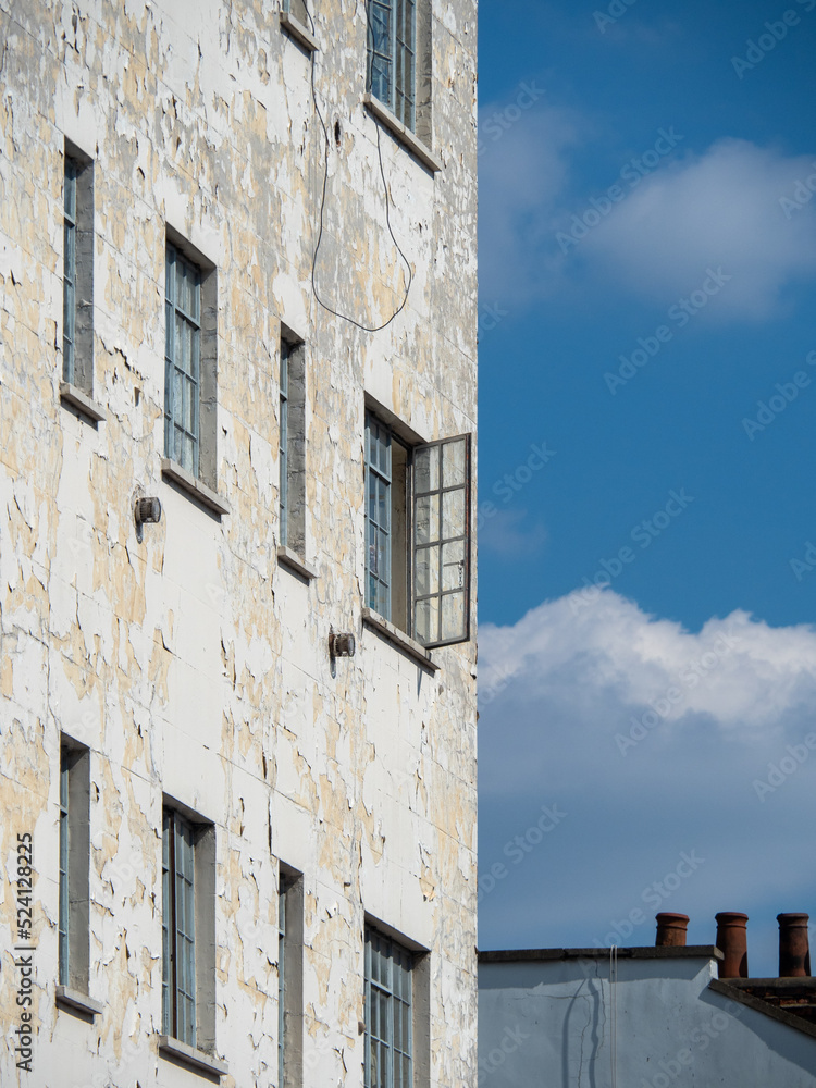 A dilapidated building with an open window A dilapidated building with an open window