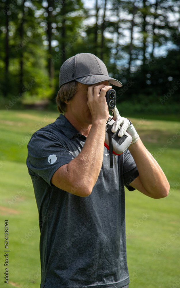 Male golfer using golf distance tool Male golfer using golf distance tool
