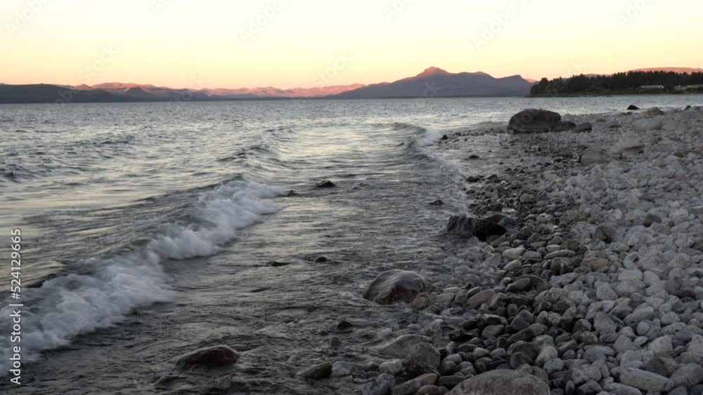 Magical view of the rocky beach, lake and mountains in the horizon, with an enchanting sunset light. Magical view of the rocky beach, lake and mountains in the horizon, with an enchanting sunset light.