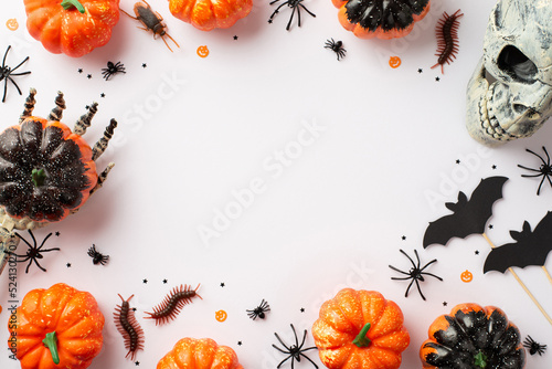 Halloween party concept. Top view photo of skeleton hands holding pumpkins skull bat silhouettes spiders cockroach centipedes and confetti on isolated white background with copyspace in the middle