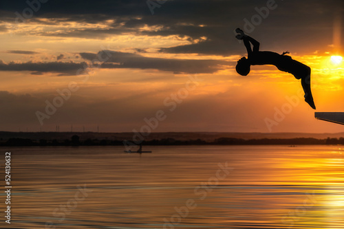 Kind macht Rückwärtssalto in einem See bei Sonnenuntergang © Ralf Geithe