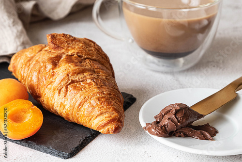 Fresh croissant with apricots, chocolate spread and coffee. French breakfast 