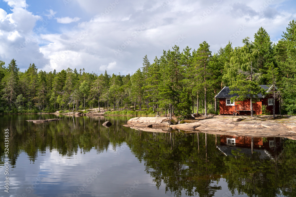 Obraz premium Stunning view of Serene and Reflecting Lake Tarnattvattnen and Remote hiking Resting Cottage in Skuleskogen National Park on a Summertime Evening with gorgeous background of Slattdalsskrevan.