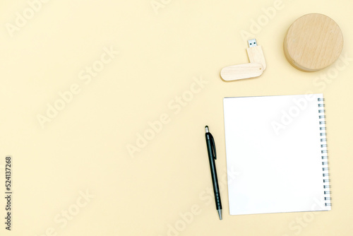 Black blank notebook, pen, glasses, goggles, flash drive top view on beige background. Top view desk arrangement. Time management, planning concept. Minimal style, mock up with copy space