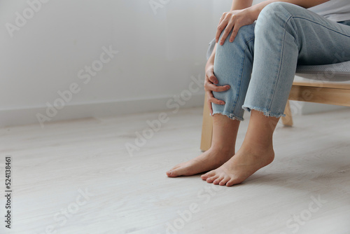 Meniscus. Closeup shot of pain leg knee suffering tanned beautiful young Asian woman touch injured knee at home interior living room. Injuries Poor health Illness concept. Cool offer Banner