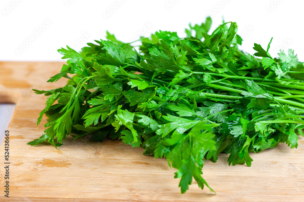 Bunch of fresh parsley and coriander vegetables on a wooden board, white background Bunch of fresh parsley and coriander vegetables on a wooden board, white background