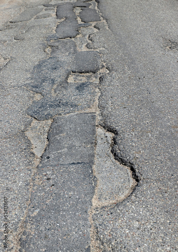 An old paved road with a lot of holes and damage © rsooll