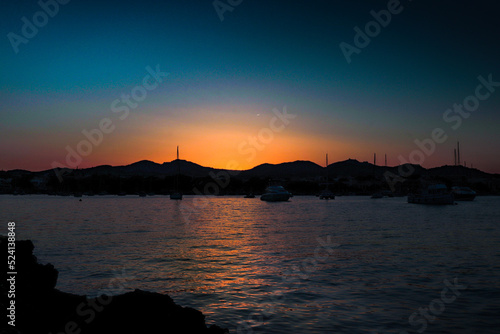 sunset in portocolom with the sea and boats in the background photo