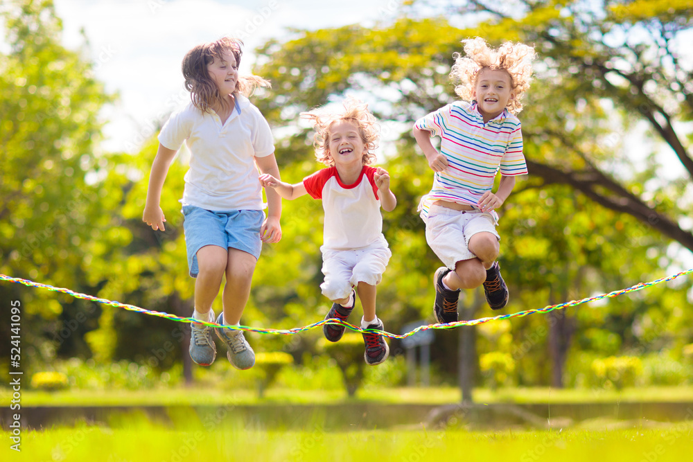 Happy kids play outdoor. Children skipping rope. Stock Photo Adobe Stock