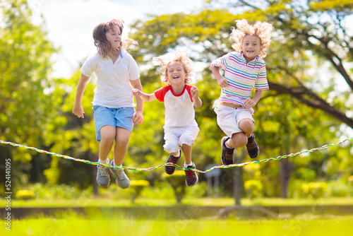 Happy kids play outdoor. Children skipping rope. photo