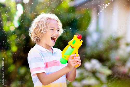 Kids with water gun toy in garden. Outdoor fun. photo
