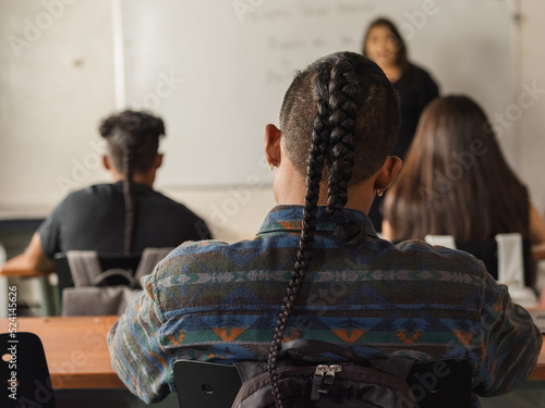 Native boy leans head to the right while writing notes in class