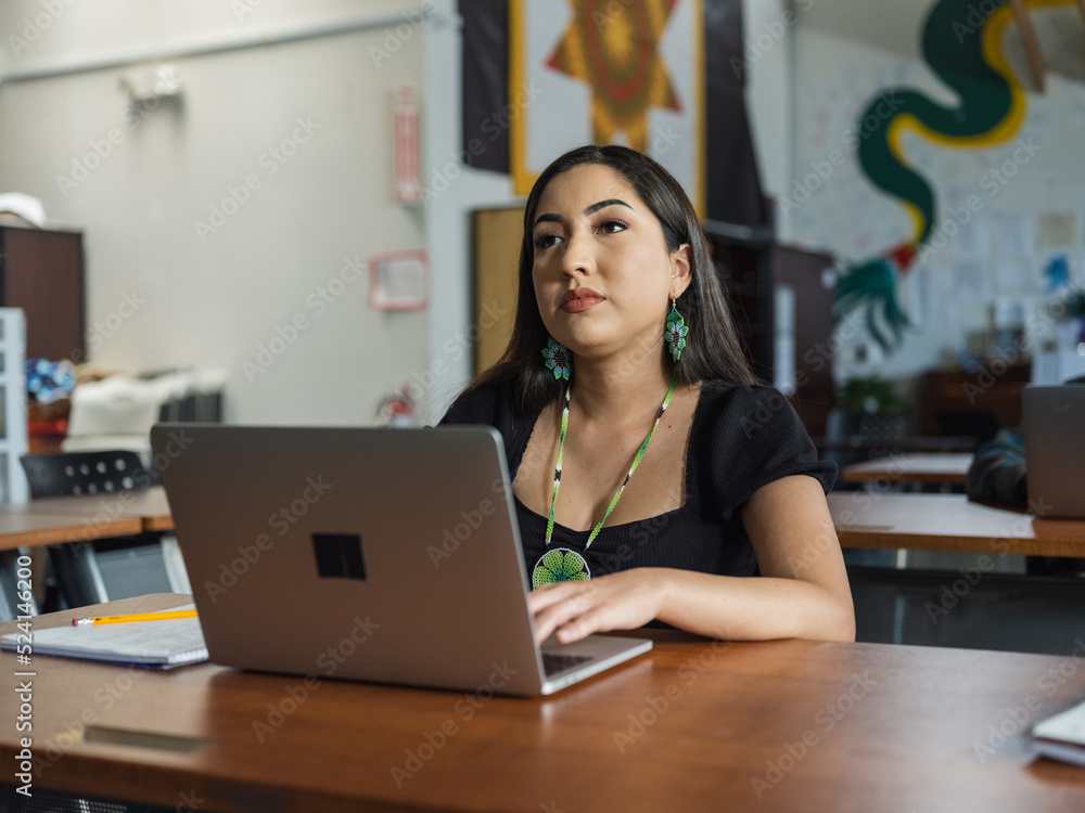 Fototapeta premium Wide angle of a Native girl student on her computer during class while looking up