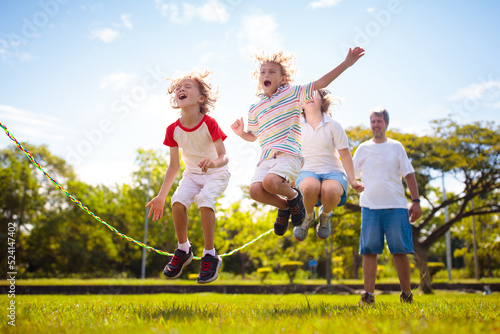 Quadro su tela Happy kids play outdoor. Children skipping rope.