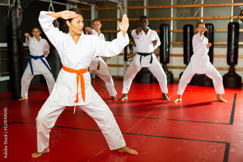 Asian woman in kimono standing in fight stance during group karate training.