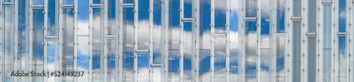 Reflection of blue sky and white clouds in a shiny wall, as a graphic background 