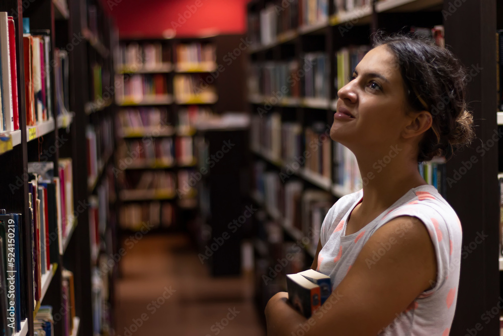 Portrait of beautiful girl standing in university library. Searching information for a project, learning for passing exams, education concept Portrait of beautiful girl standing in university library. Searching information for a project, learning for passing exams, education concept
