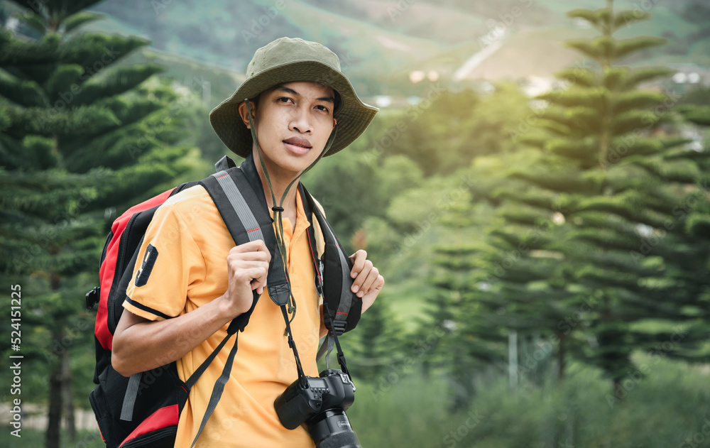 Young man traveler with photo camera and backpack hiking outdoor, on vacation in the mountains background. Travel and lifestyle concept