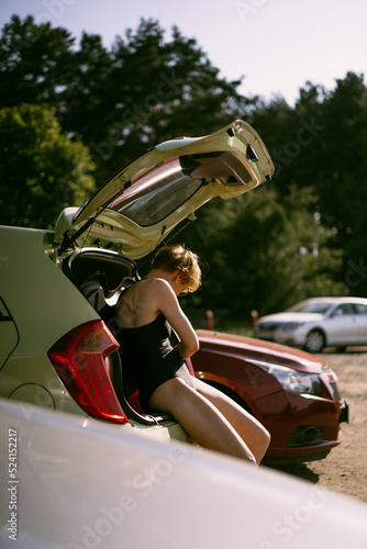 Fototapeta Naklejka Na Ścianę i Meble -  Beautiful young woman changing clothes near the car.
