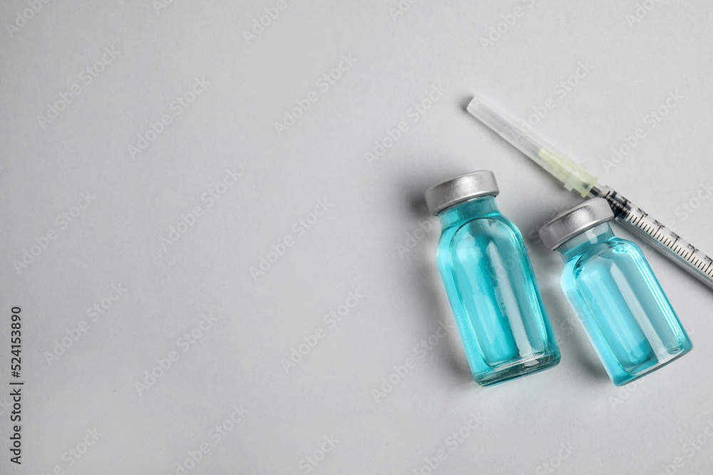 Vials and syringe on light background, flat lay with space for text. Vaccination and immunization Vials and syringe on light background, flat lay with space for text. Vaccination and immunization